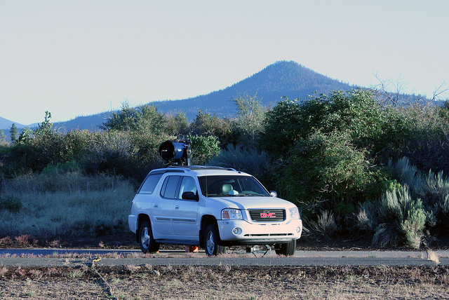 A white SUV with a large telescope on a roof-mounted lift, parked at Hat Creek Radio Observatory